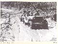 BOUGAINVILLE, 1945-07-16. A JEEP PULLING A TRAILER LOADED WITH 44-GALLON DRUMS FOR COLLECTING WATER FROM THE OGORATA RIVER, NEGOTIATING A MUDDY SECTION OF THE BUIN ROAD EAST OF THE RIVER