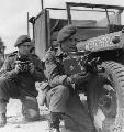 M5535245 AFPU cameramen Sgt Harry Oakes (left) and Sgt Bill Lawrie kneeling with their stills and movie cameras alongside a jeep.